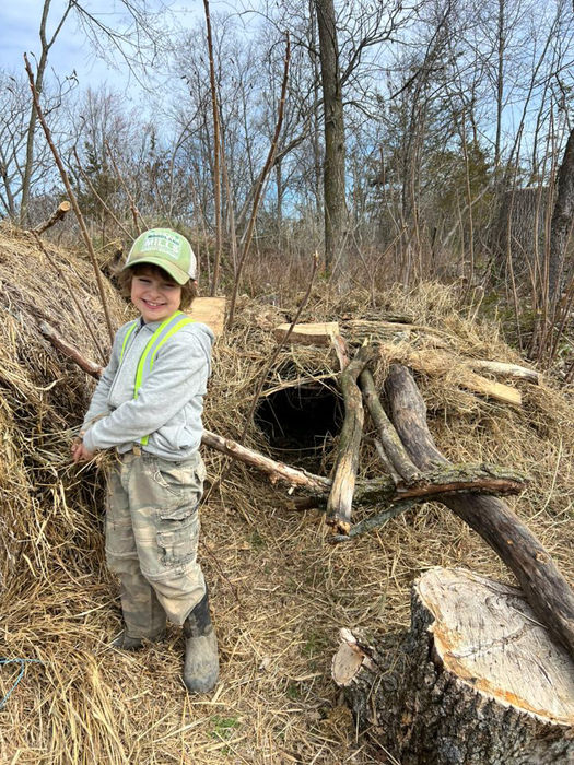 Child building a haybale cave with sticks