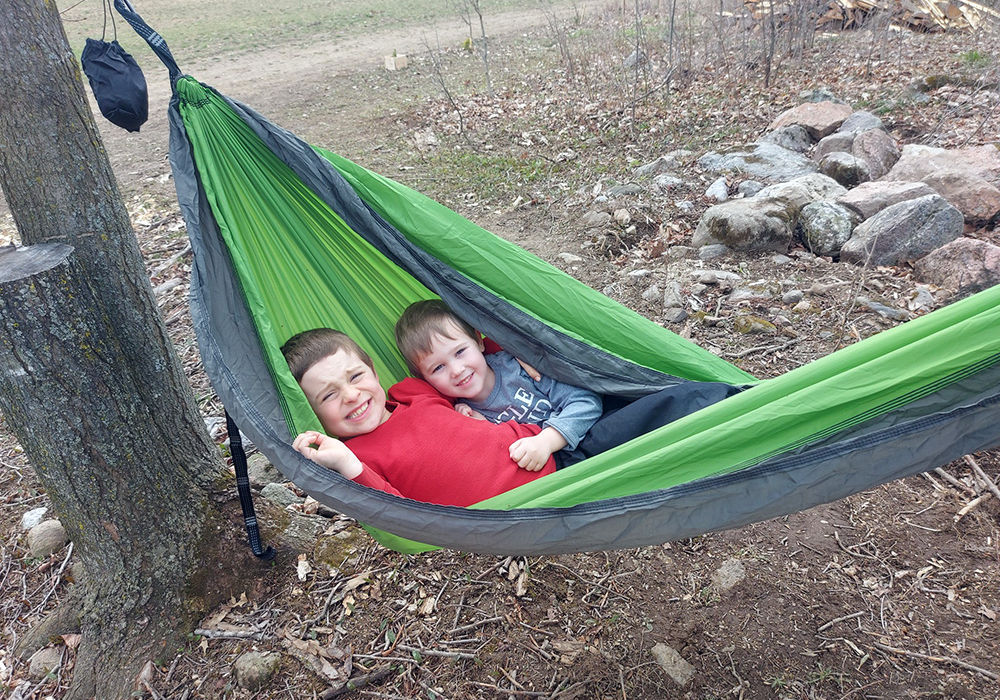 Two kids swinging in green hammock
