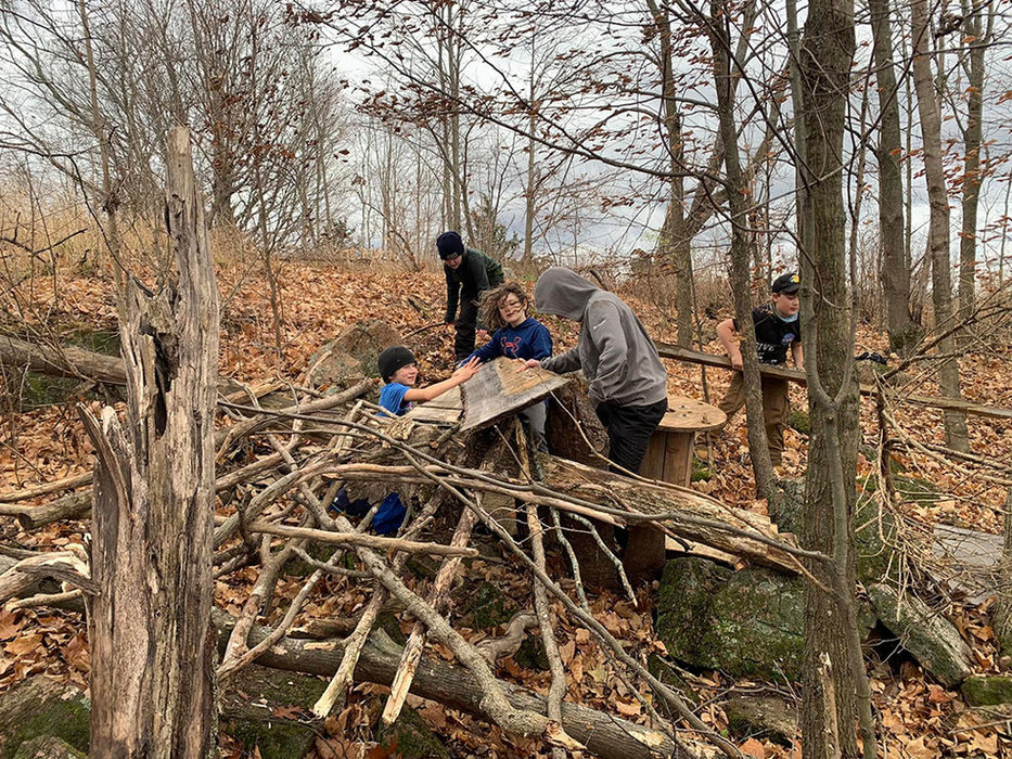 Children creating an elaborate fort with sticks in the woods