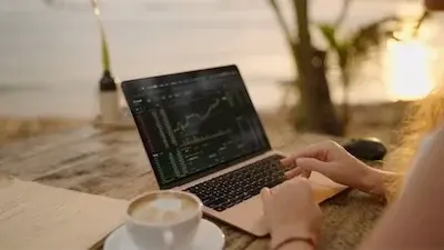 Person typing on laptop showing trading screen