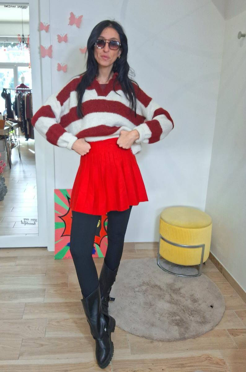 Donna con occhiali e maglione a righe rosse, posa e gonna rossa.