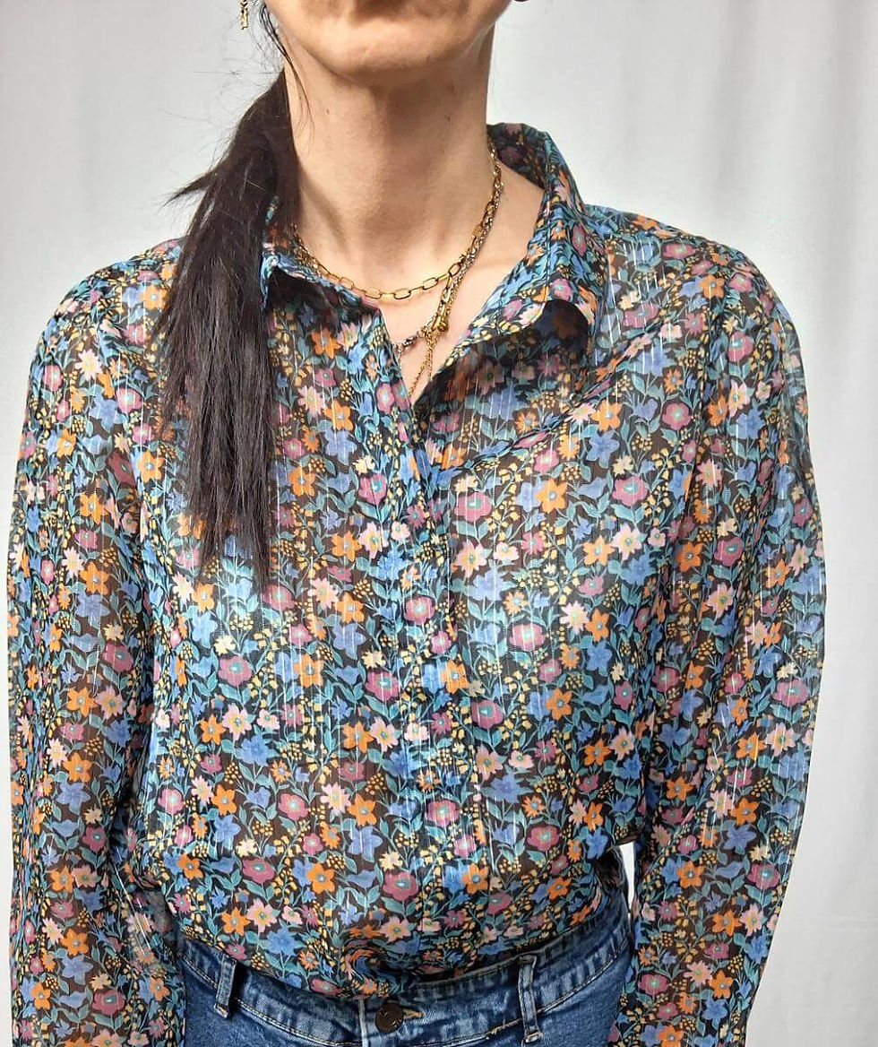 Woman wearing floral shirt with visible necklace and buttons on white backdrop.