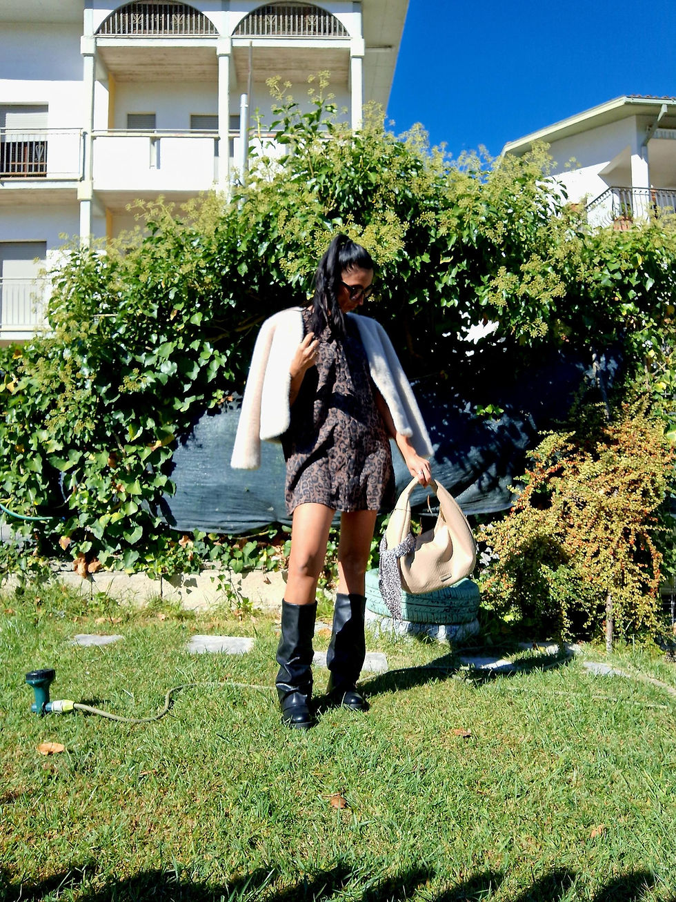 Donna in abito e stivali con borsa Cardigan Leo dietro le foglie