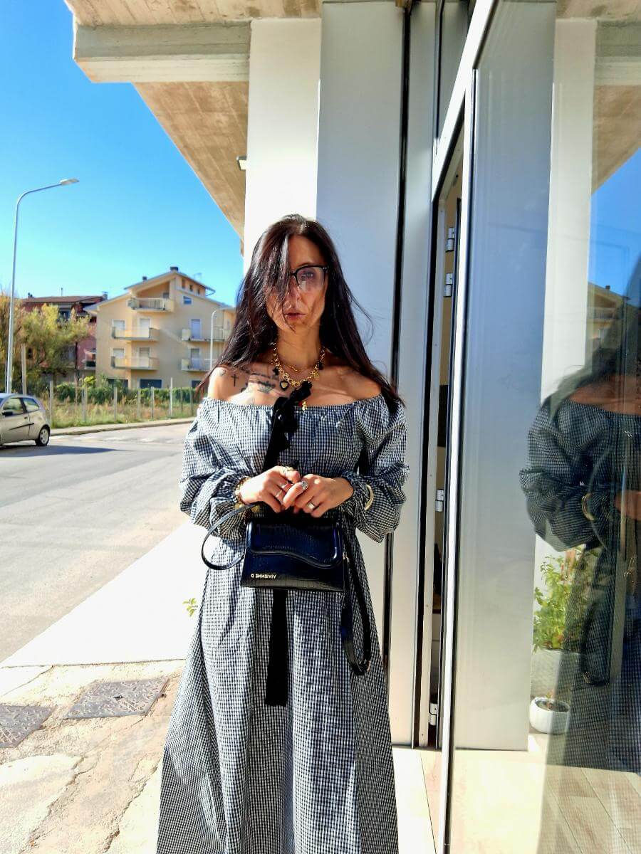 Miniatura: Dora in a black and white dress with a black bag outside is smiling