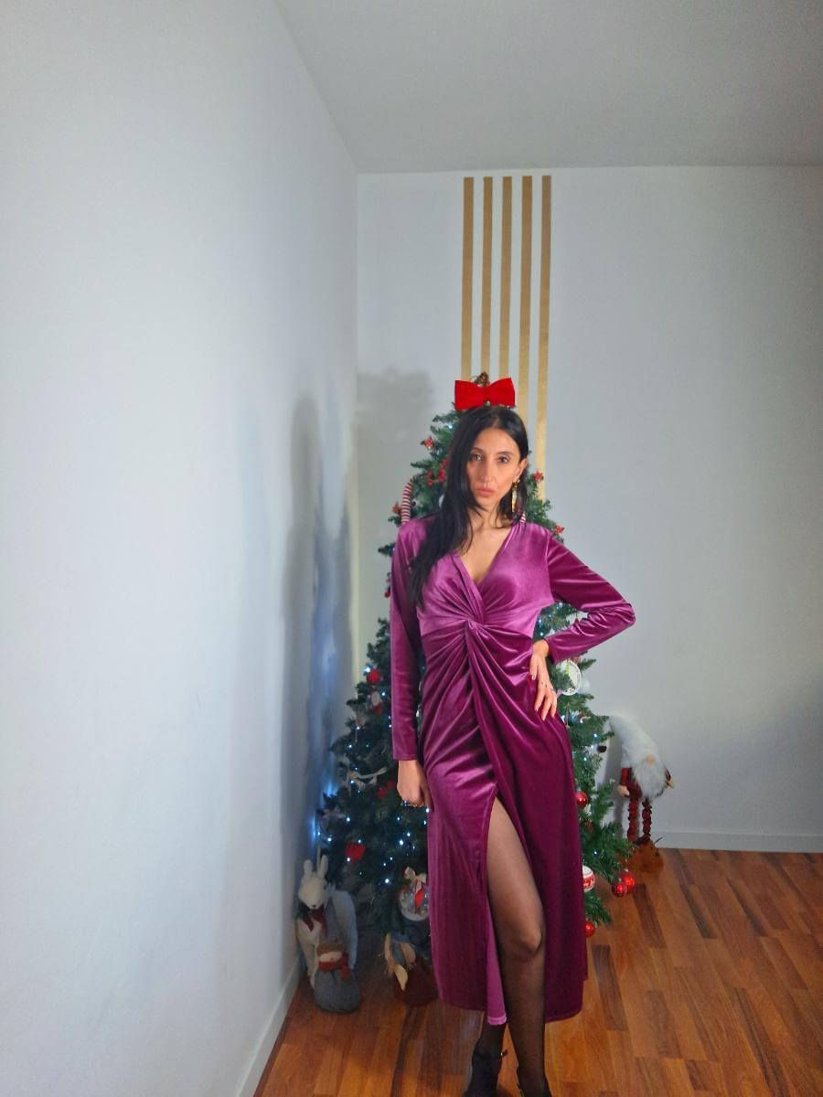 Donna che indossa un abito lungo rosa davanti a un albero di Natale.