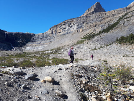 Randonneuse dans un cirque galciaire avec une chute au loin