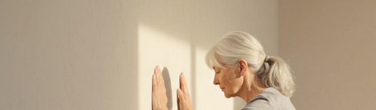 Close-up view of an older adult doing a wall push-up at home.