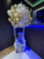 Teddy bear in hot air balloon with balloons, party decoration inside room.