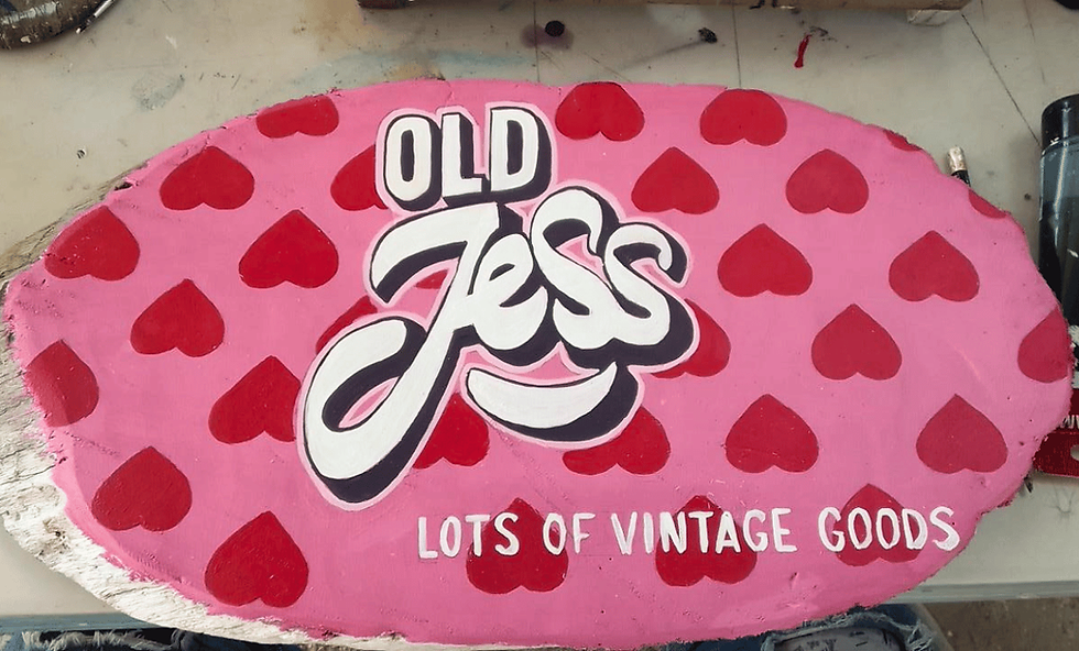 Custom driftwood sign with logo painted on a driftwood sign in colorful design at Tugboat Beach