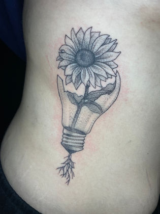 Stippled dotwork tattoo of a sunflower growing from a lightbulb