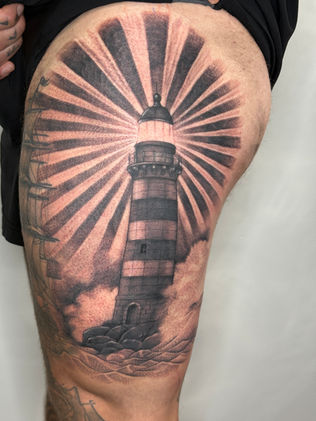 black and grey neo traditional tattoo of a lighthouse on a leg