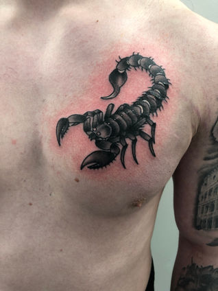 Black traditional tattoo of a scorpion on a chest
