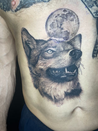 Black and grey realistic tattoo of a wolf and moon