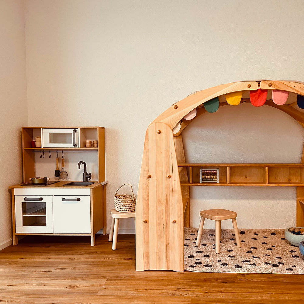 Spielküche und Waldorf-Spielständer mit sorgfältig ausgesuchten Spielmaterialien (Holzspielzeug, Stapelsteine, etc.).
