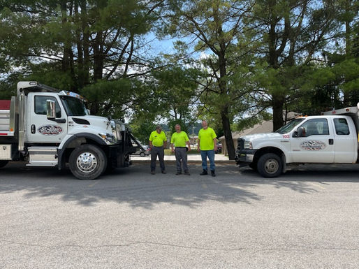 Four workers stand between two trucks