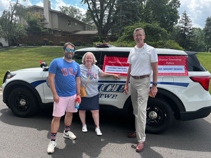 Three people by a police SUV with red signs