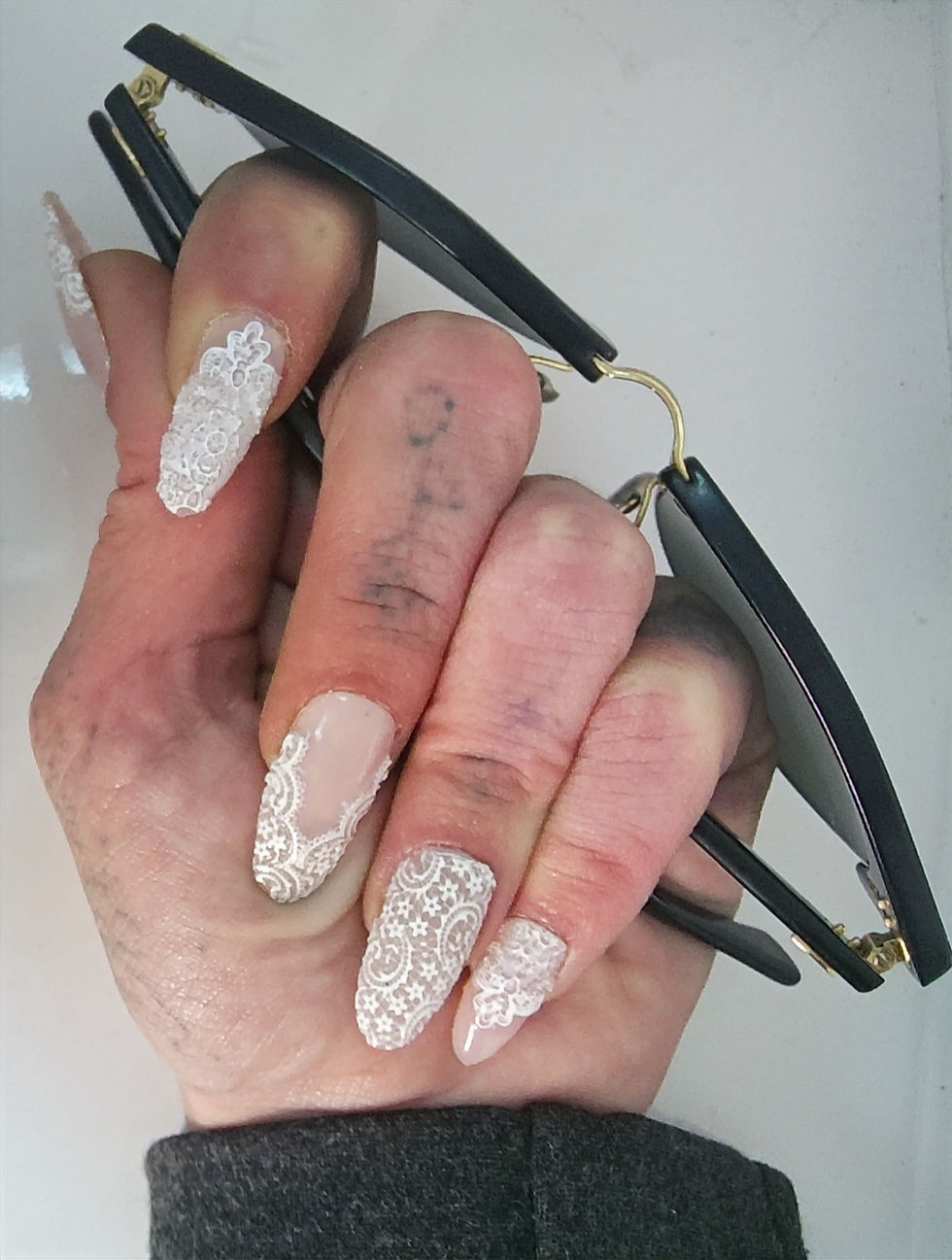 Lace press-on nails with intricate white lace detailing on a blush nude base by Pressiva