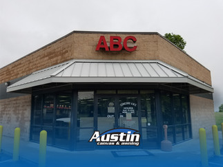 Standing seam hipped awning installed at an ABC store, with Austin Canvas & Awning logo at the bottom.