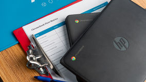 Two Chromebooks resting on a clipboard with a fleet metrics tracking sheet.