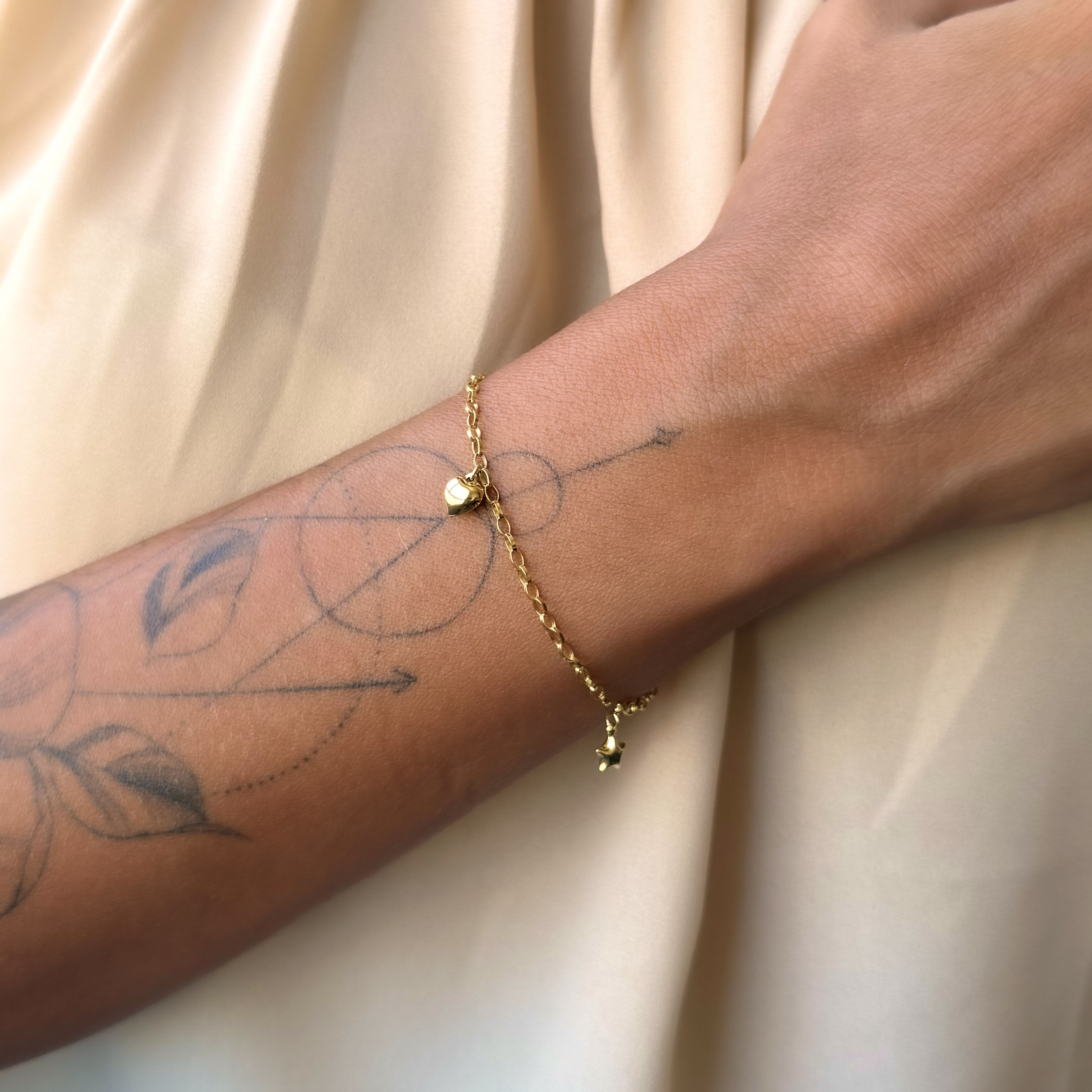 Pulseira com pingentes de coração e estrela bojuda pendurados em ouro 18k.