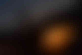 Silhouette of man crouched ontop of a rock pillar with a dark night sky ontop and a bright orange sunset below