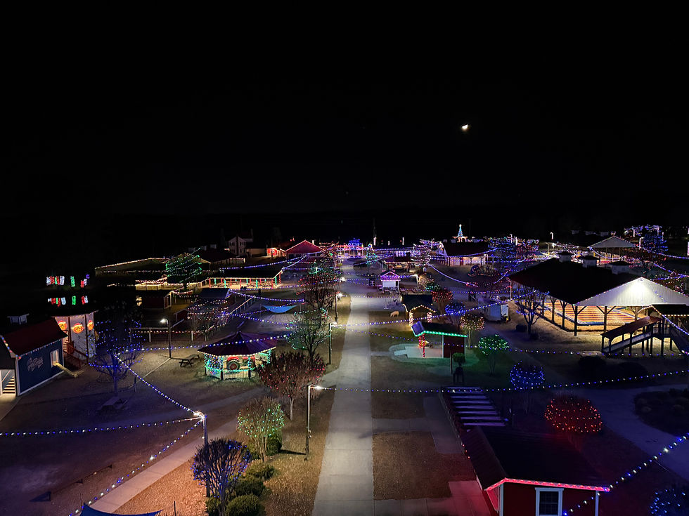 Night aerial view of a village illuminated with colorful lights under moon.