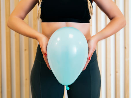 Person holding a balloon in front of the pelvis to visually represent pelvic floor muscle engagement, control, and strengthening exercises.