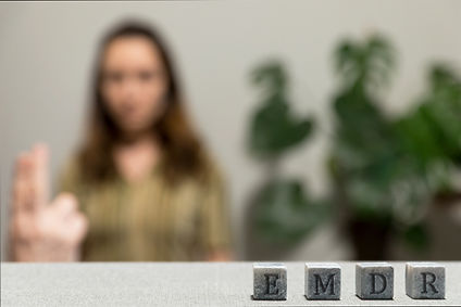 Letters EMDR written on grey stone cubes blocks Female looking at therapist fingers in blu...ted.jpg