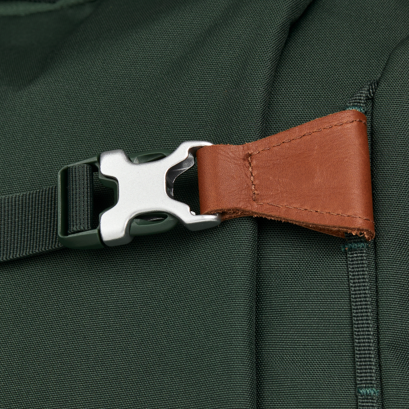 Miniaturbild: Detail von Schulrucksack in dunkelgrün mit einer Schnalle in Leder und Metall und Griff