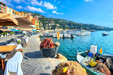 Panoramic cityscape with street cafe and fishing boat  in resort town Villefranche sur Mer