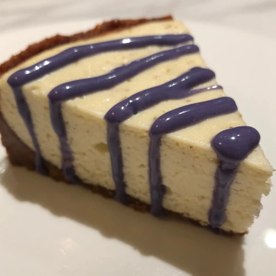 slice of lavender cheesecake with purple white chocolate topping that was cooked in instant pot