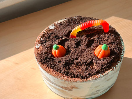 halloween tiramisu dessert with oreos, candy pumpkins and gummy worm for dirt cup and graveyard effect