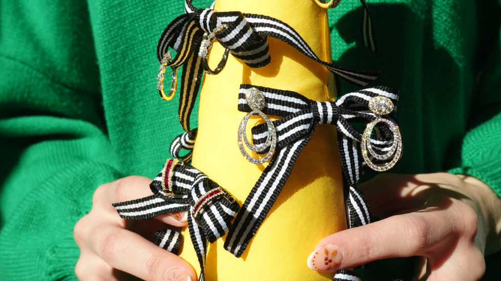 Fine diamond earrings displayed on a ribbon-wrapped holiday tree, photographed for a luxury Christmas jewelry campaign.