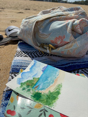 watercolor landscape painting inspired by coastal scenery, featuring layered blues, greens, and soft horizon lines. watercoloring on the beach