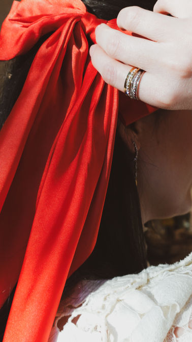 Fine jewelry styled with a red holiday bow in a vintage-inspired Christmas editorial photoshoot.