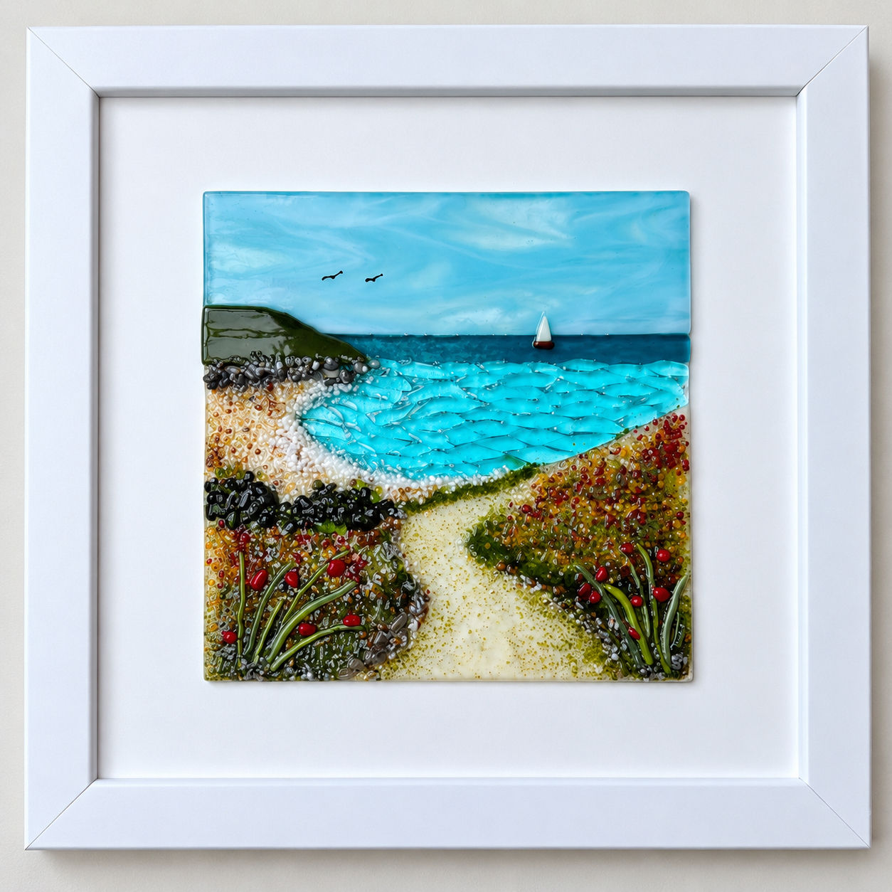 Handmade fused glass coastal seascape with winding path, wildflowers, turquoise seas and sailing boat.