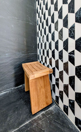 shower bench in shower with black and white tile wall