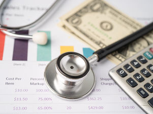 Healthcare finance concept with stethoscope, calculator, U.S. dollar bills, and printed cost analysis charts — representing medical billing, compliance, and healthcare economics.