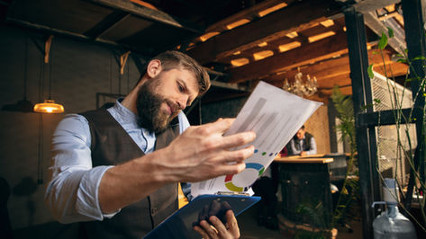 Group of professionals in a business meeting reviewing financial charts, graphs, and documents around a table — emphasizing collaboration, compliance, and strategic decision-making.