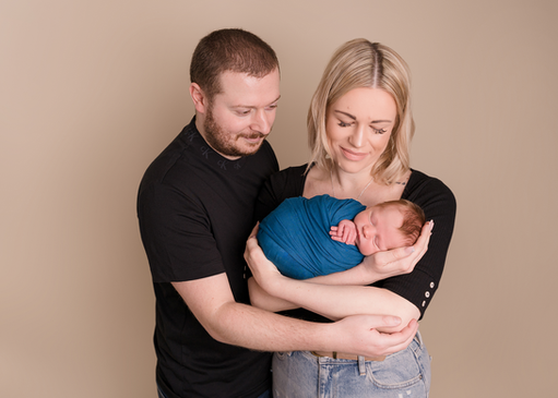 Family portrait with baby photographed in a neutral studio setting in Derbyshire