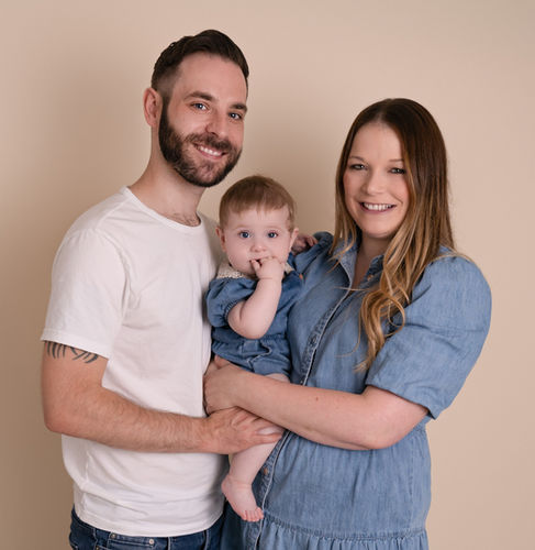 Family portrait with baby photographed in a neutral studio setting in Derbyshire