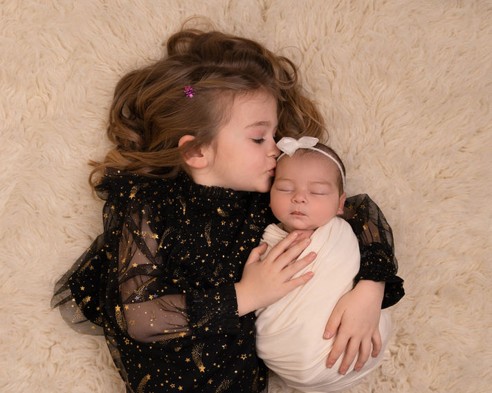Older sibling cuddling a newborn during a family photoshoot in Derbyshire