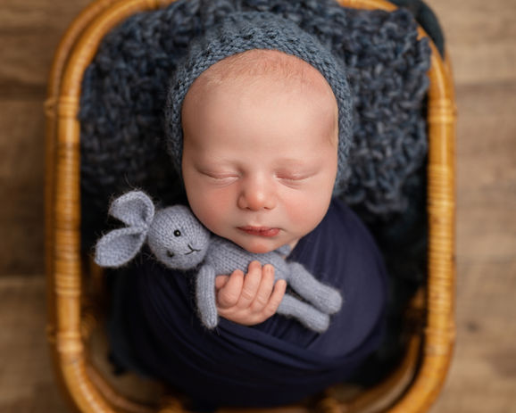 Newborn baby wrapped in navy blue with a soft toy bunny, captured at a newborn photography studio in Derbyshire