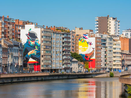 Liège, Belgium — city buildings with street art on the sides overlooking a river.