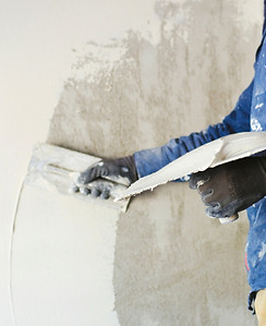 homme qui pose du plâtre sur un mur