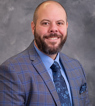 Smiling man in a suit against a professional backdrop.