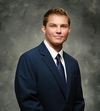 Young professional man in blue suit smiling for a portrait.