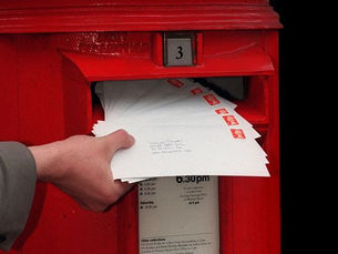 someone posting letters into a red postbox