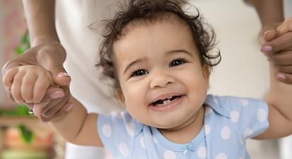 Photo of baby holding hands, smiling.