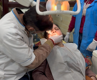 Dentist in white lab coat, performing Root Canal Treatment on a middle aged woman 